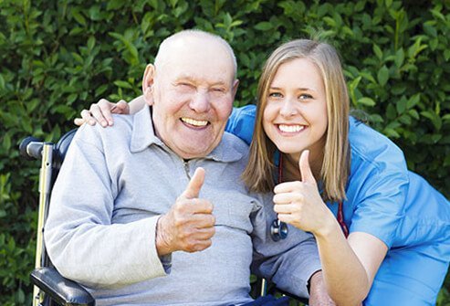 A senior patient and nurse giving a thumbs up.