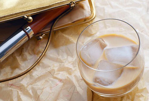 Mixed drink next to an evening bag with lipgloss.