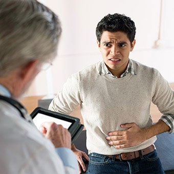 A patient describing painful abdominal symptoms to his doctor.