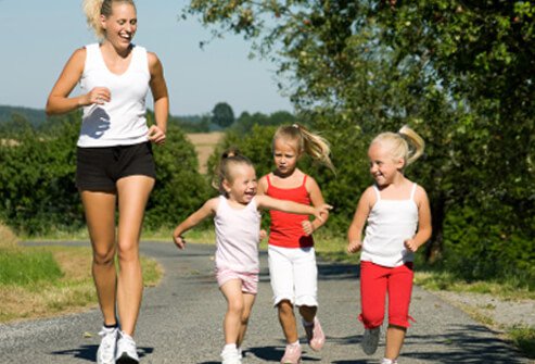 A mom jogs with her daughters.