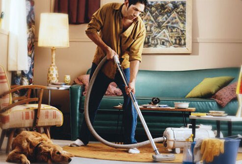 Photo of man cleaning with dog nearby.