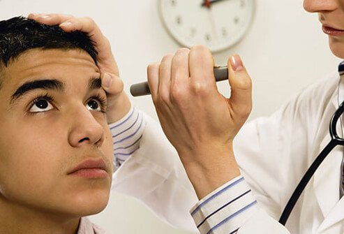 A doctor checks a young male patient's eye.