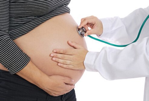 A doctor examines a pregnant woman's belly.