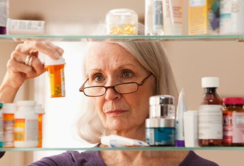 A senior woman reading the dosage of a prescription medication bottle.