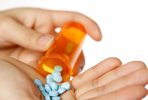 A woman pours prescriptions pills in to her hand.