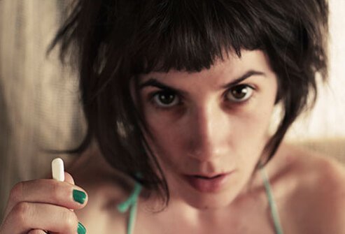 A young woman with a pill in her hand.
