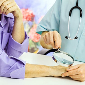 A doctor examines a patient's hands for scabies.