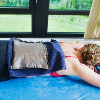 A woman uses an ice pack on her back to relieve her sacroiliac (SI) joint pain.