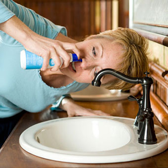 A woman using a sinus rinse kit.