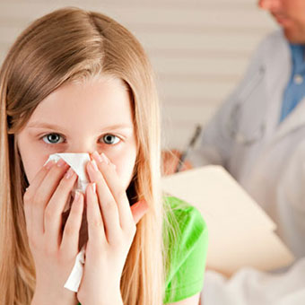 A girl blowing her nose at a doctor's office.