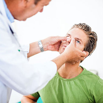 An ENT doctor using a rhinoscope to examine the nose of a patient.