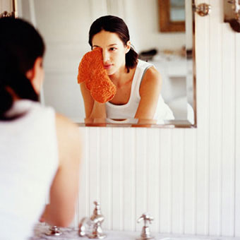 A woman removes eye makeup.