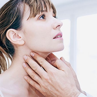 A doctor examining a woman's neck for swollen lymph nodes.