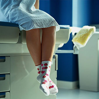 A female patient waits on an examination table.