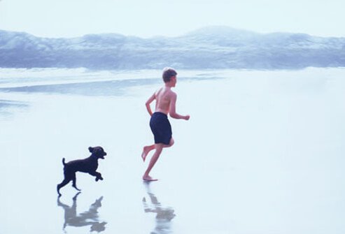Boy and Puppy Running on Beach.