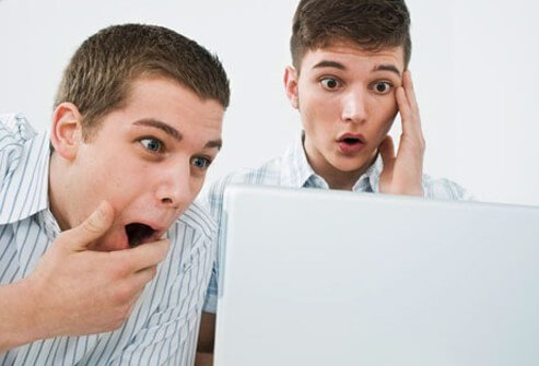 Surprised teen boys look at a computer screen.