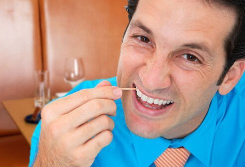 A man picking his teeth with a toothpick. 