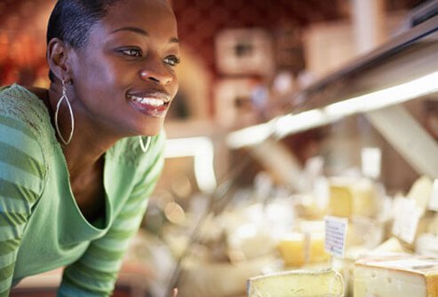 A woman looking into a cheese display case.