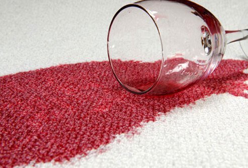 A spilled glass of red wine on white carpet. 