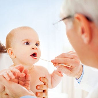 A doctor examines a baby's throat and mouth.