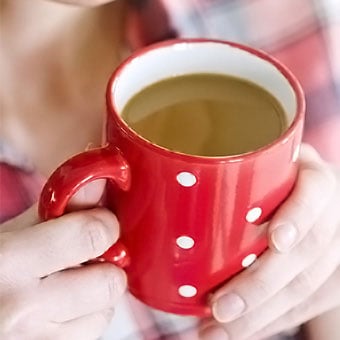 A person holds a cup of coffee.