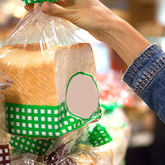 A person holds a bag of sliced white bread.