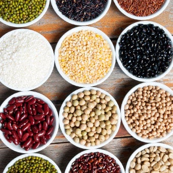 An assortment of multi-colored beans in bowls.