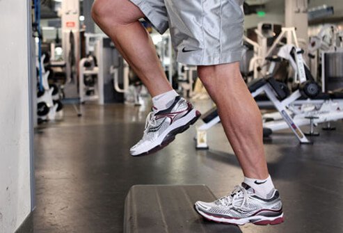 Photo of a man doing a calf raise on a step.