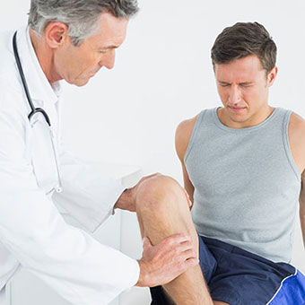A doctor examines a man's knee.