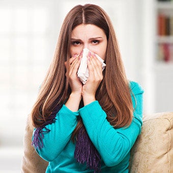 A woman with an upper respiratory infection sneezing into a tissue