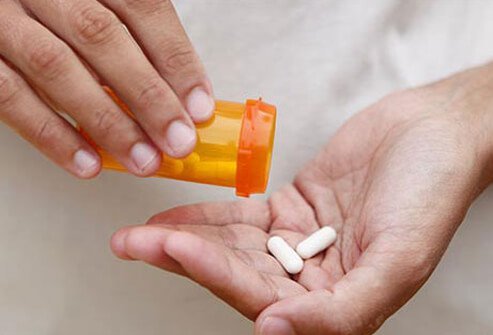 A person with pills in their hand.