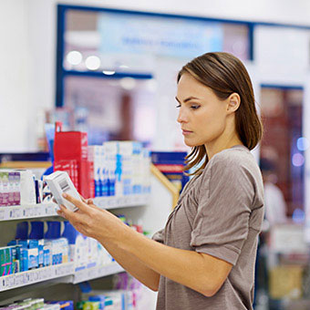 A woman reads the label of an over-the-counter wart medication at the drugstore.
