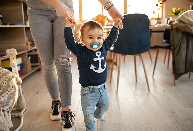 Babies typically take their first steps around 1 year of age.